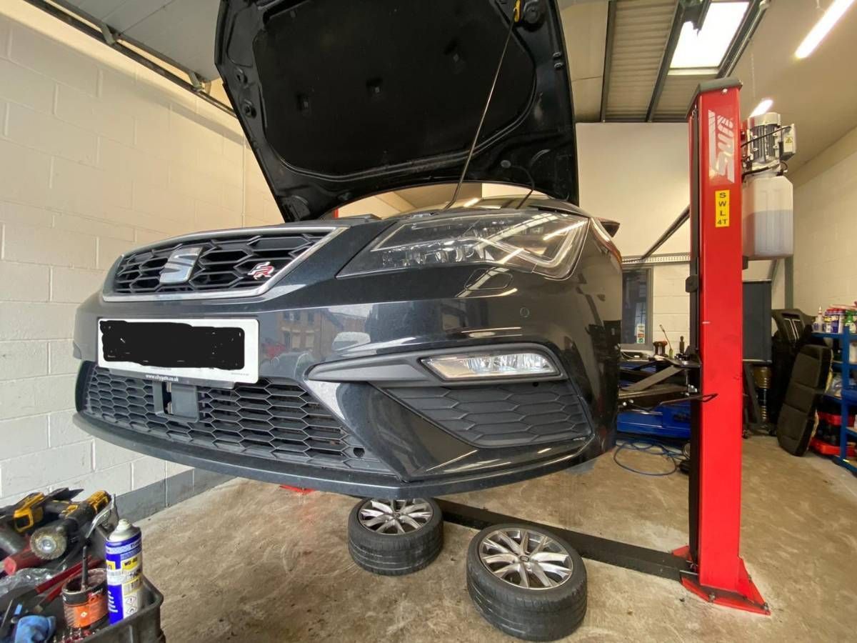 Black SEAT Leon raised on a two-post lift with the bonnet open in our Reading workshop