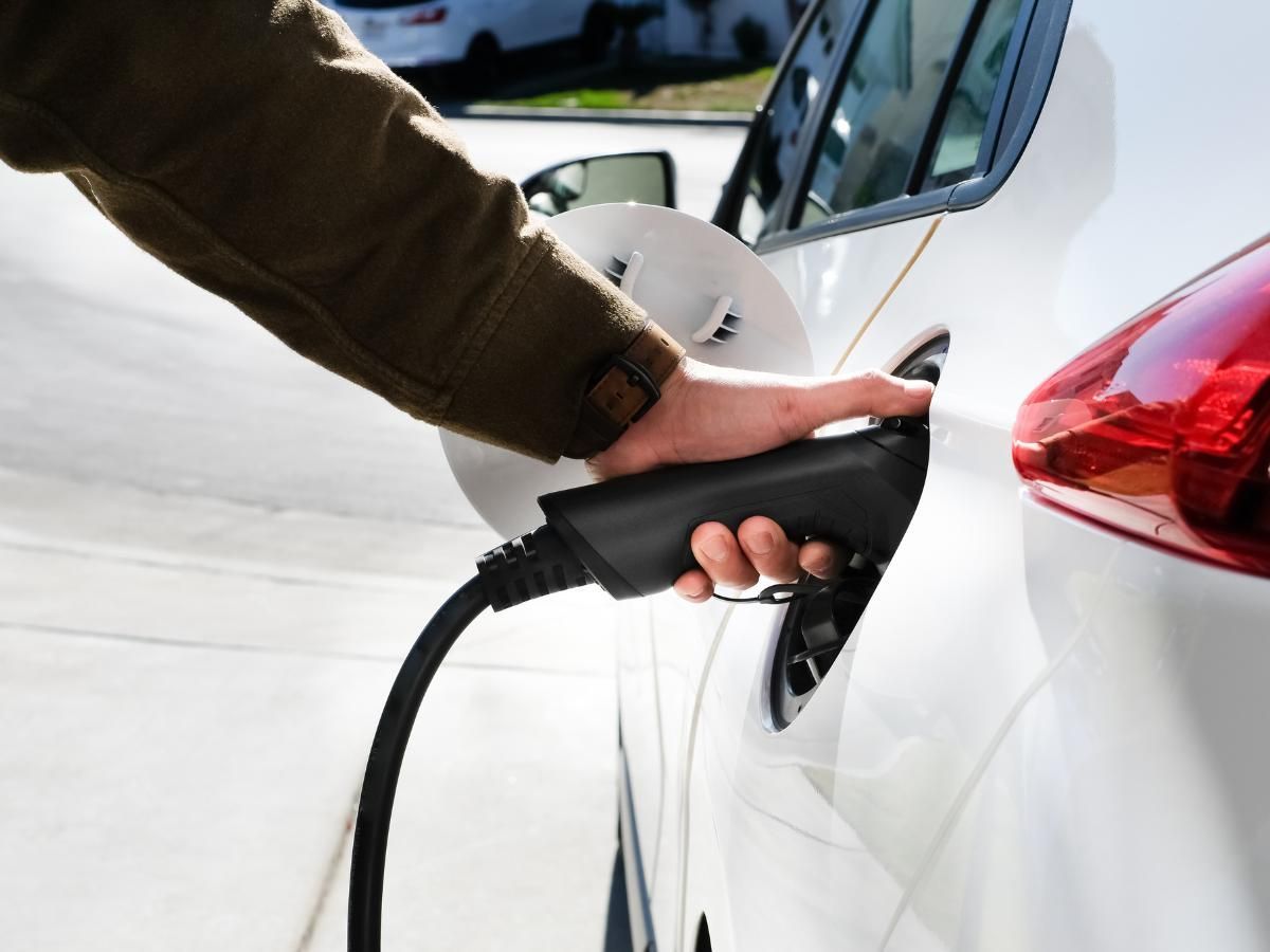 Charging cable plugged into the charging port of a white electric car