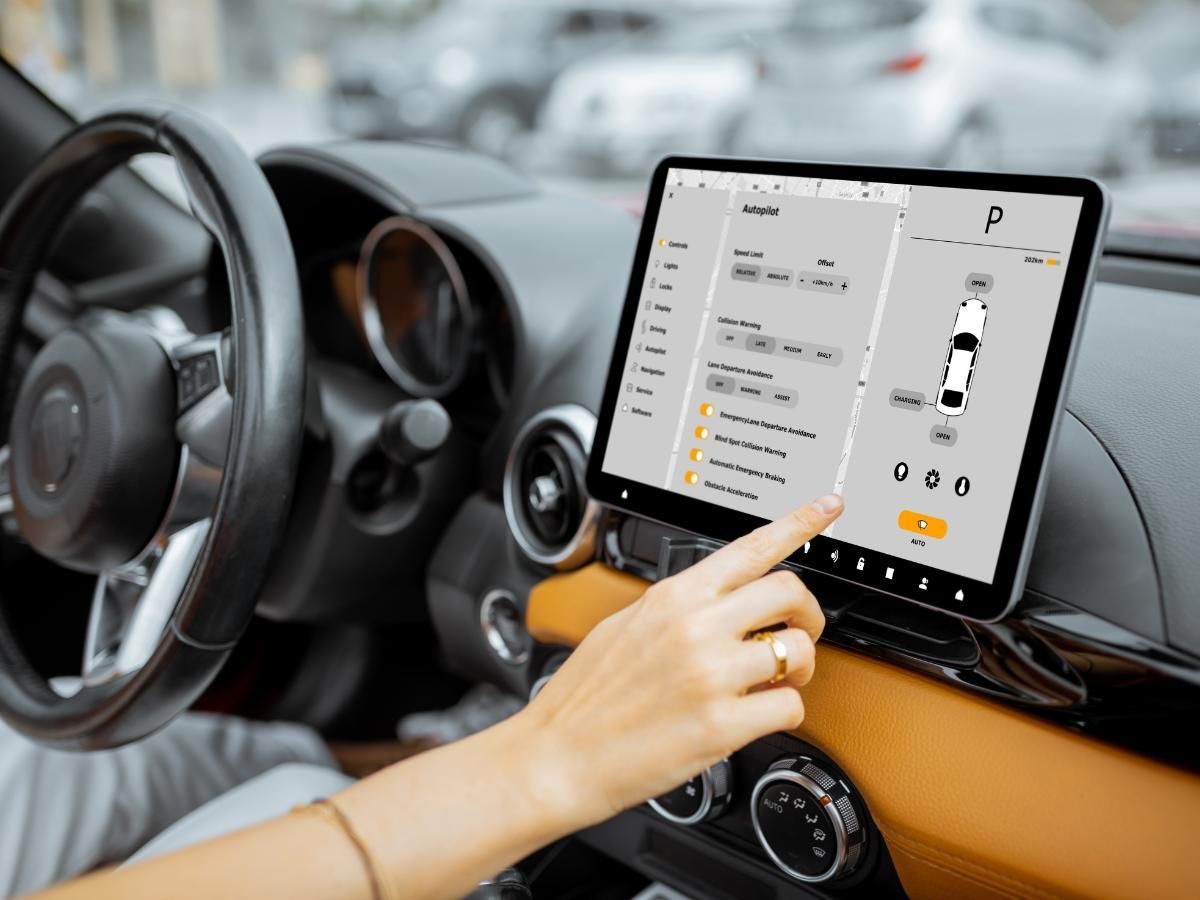 Driver touching the central touchscreen of an electric car showing its vehicle settings