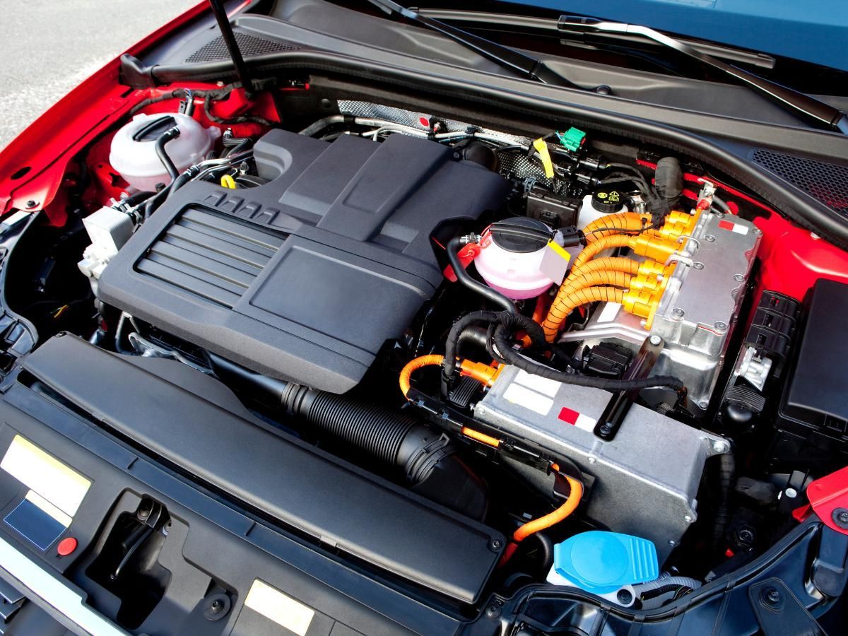 Hybrid car engine bay with orange high-voltage cables running to the power electronics