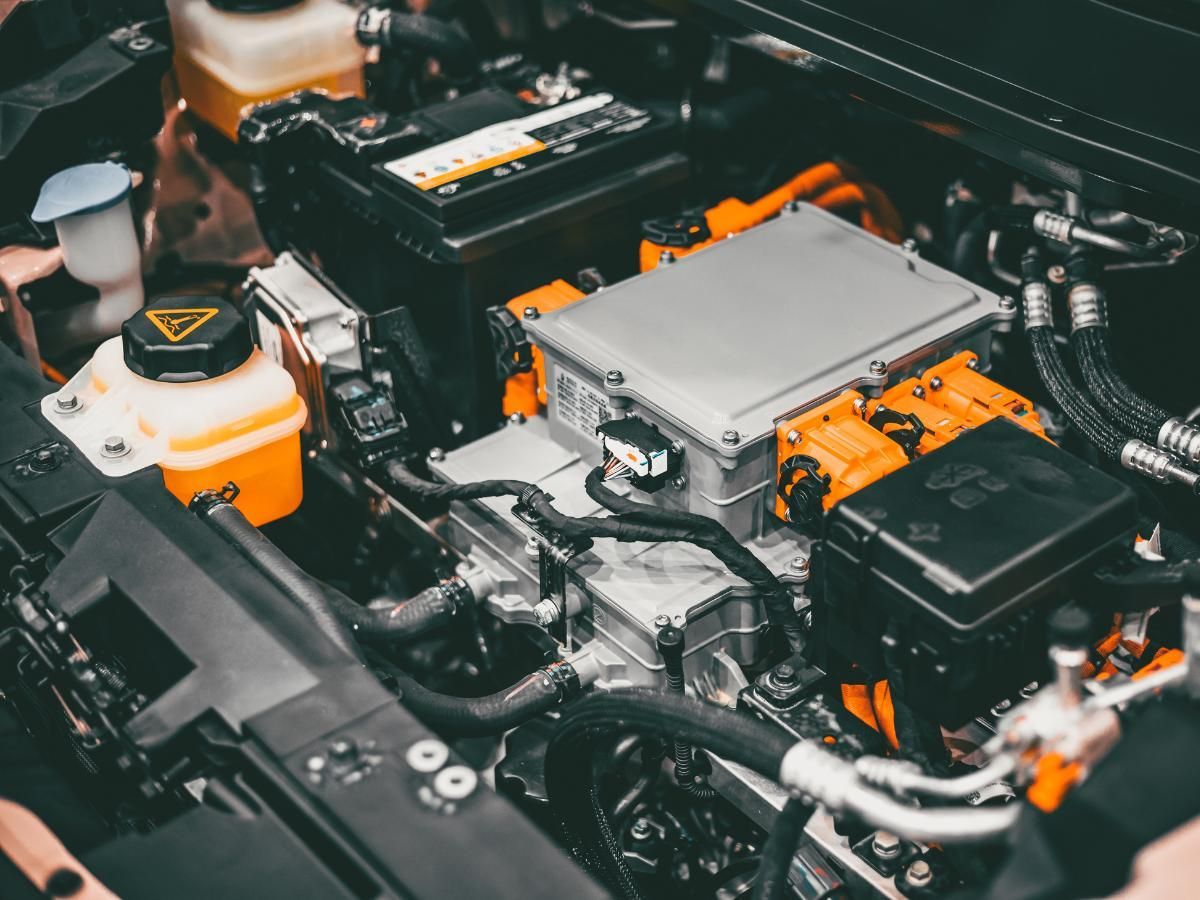Electric car power electronics under the bonnet, with orange high-voltage connectors and the coolant reservoir