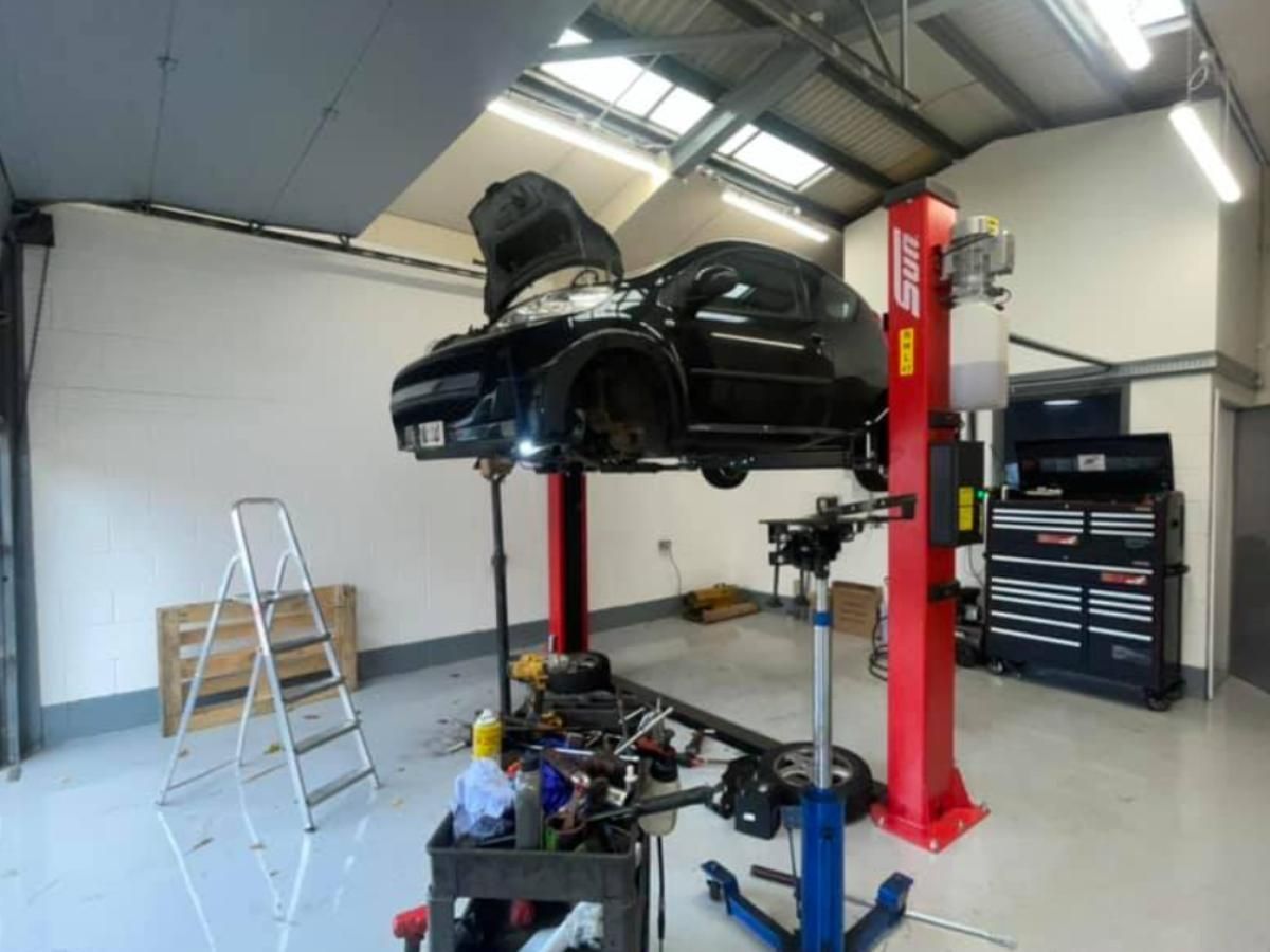 Black car raised on a two-post lift in our Reading workshop