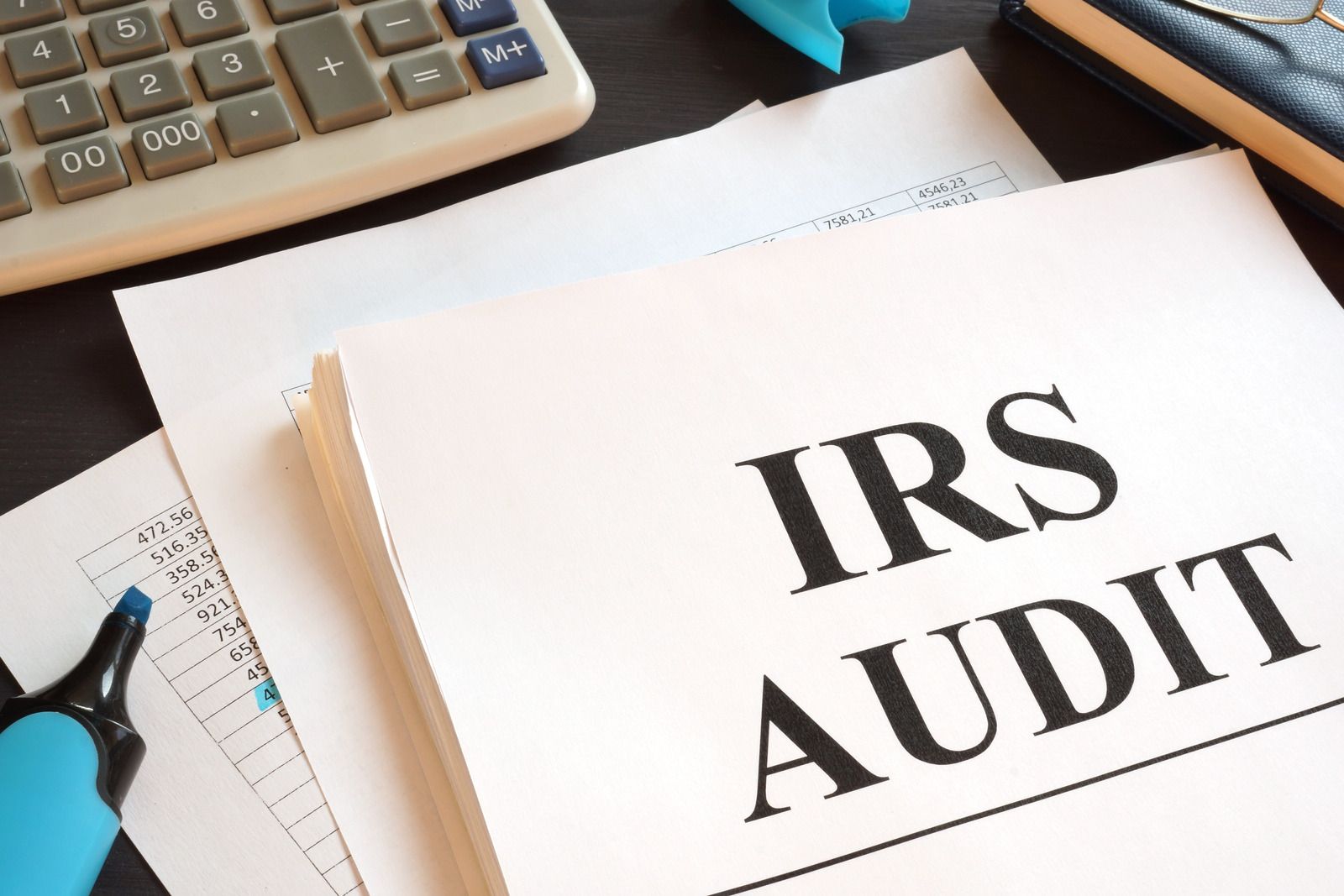 IRS audit paperwork on a desk with a calculator and pen