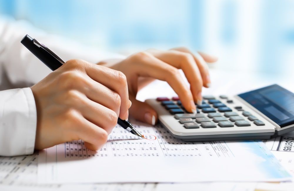 Hands using a calculator and pen on financial paperwork at a desk