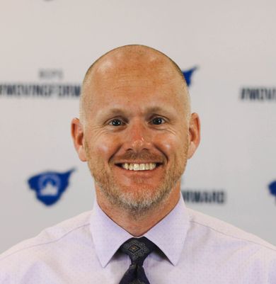 A bald man with a beard is smiling for the camera