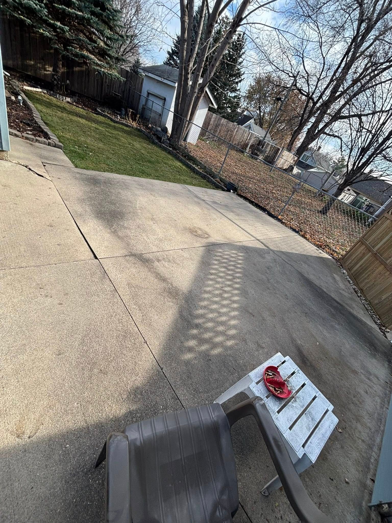 Driveway with a red-and-white bench, lawn, bare trees, and a small shed on a sunny day