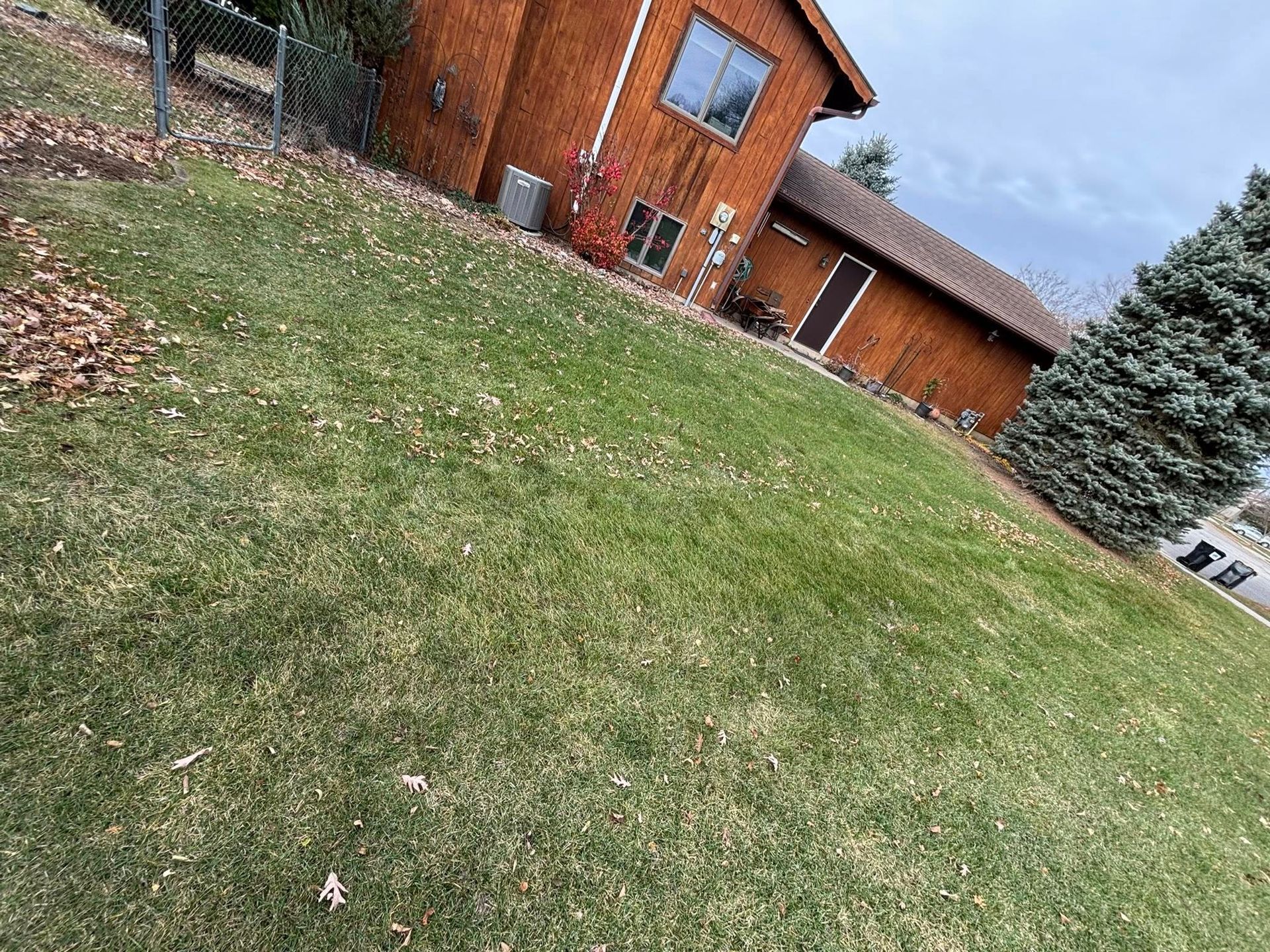 Tilted view of a grassy yard beside an orange house under a partly cloudy sky
