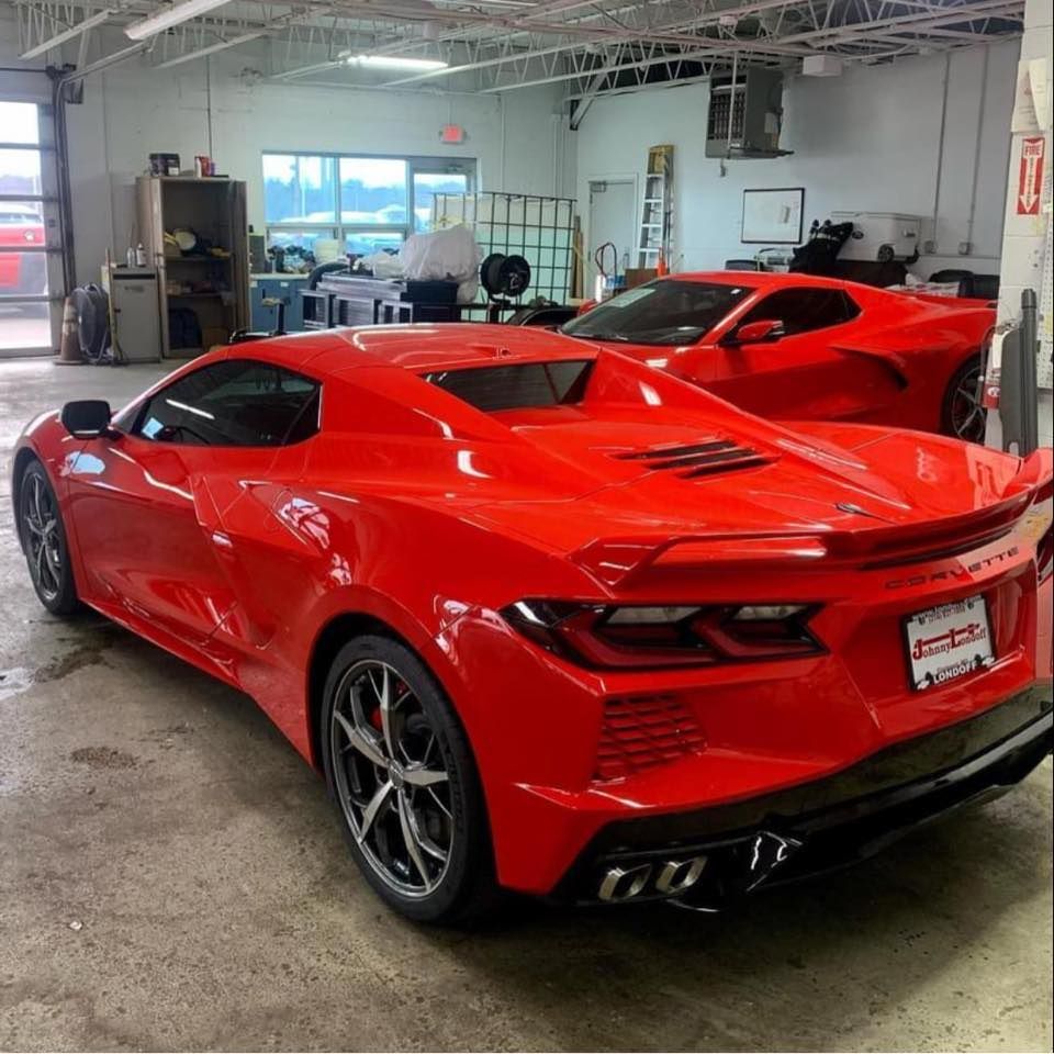 Two red sports cars are parked in a garage