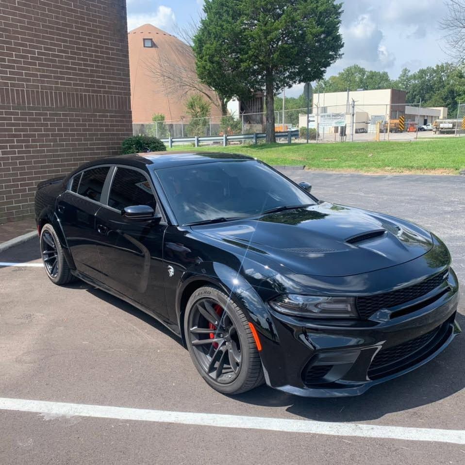 A black dodge charger is parked in a parking lot
