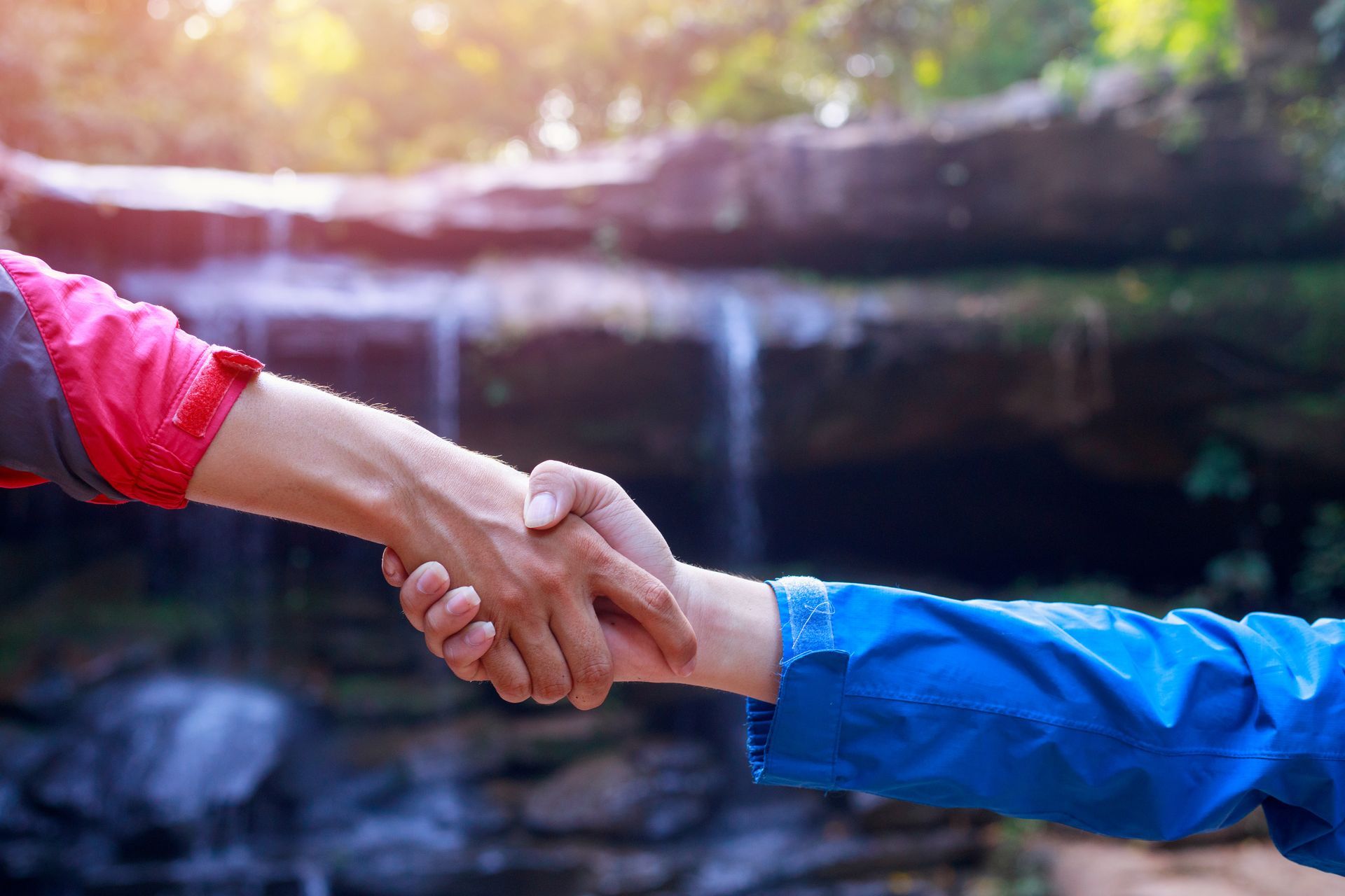 Two hands clasp eachother as one person guides another.