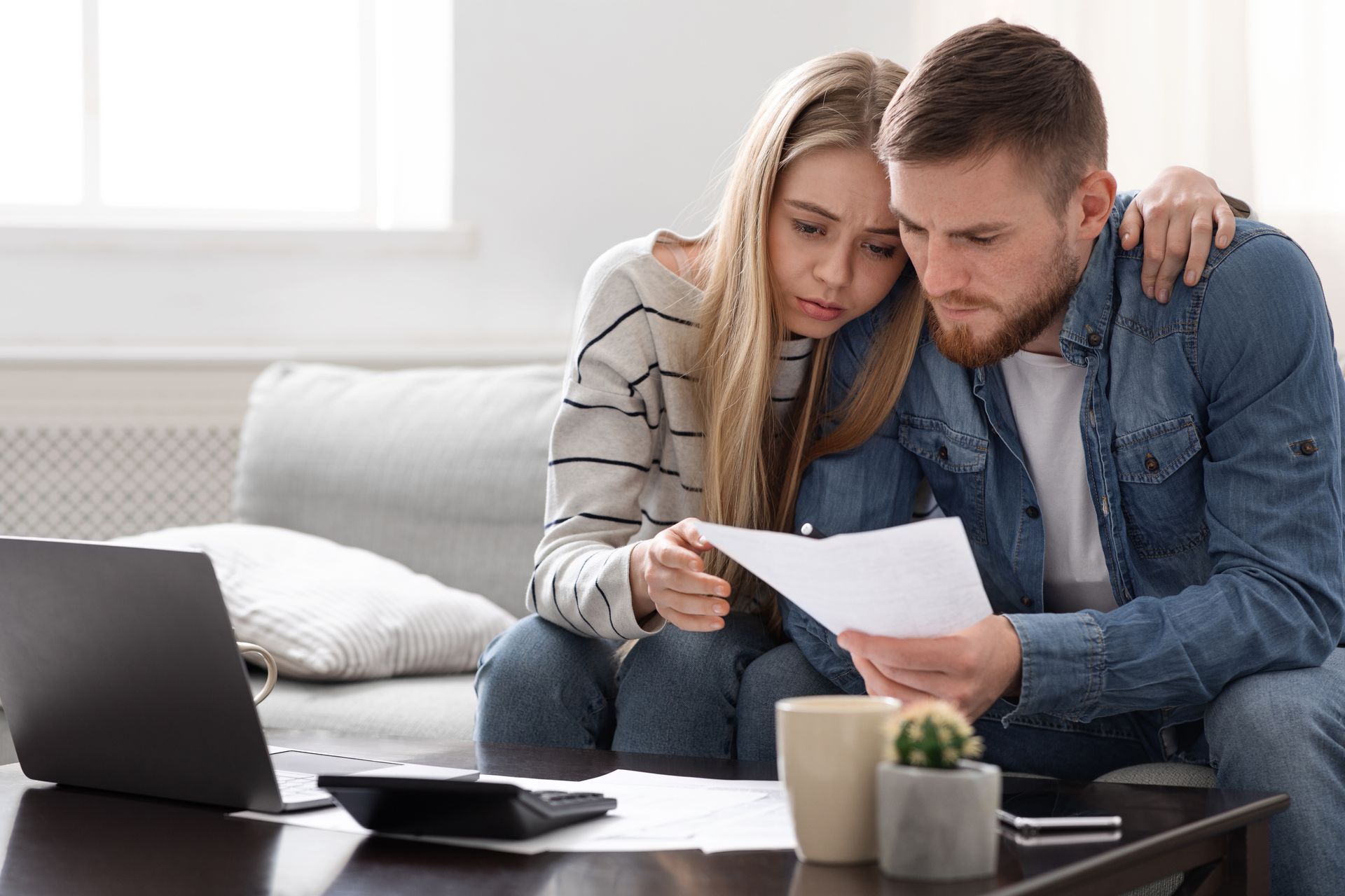 Photograph of a worried young couple sitting down to look at bills and go through their finances.