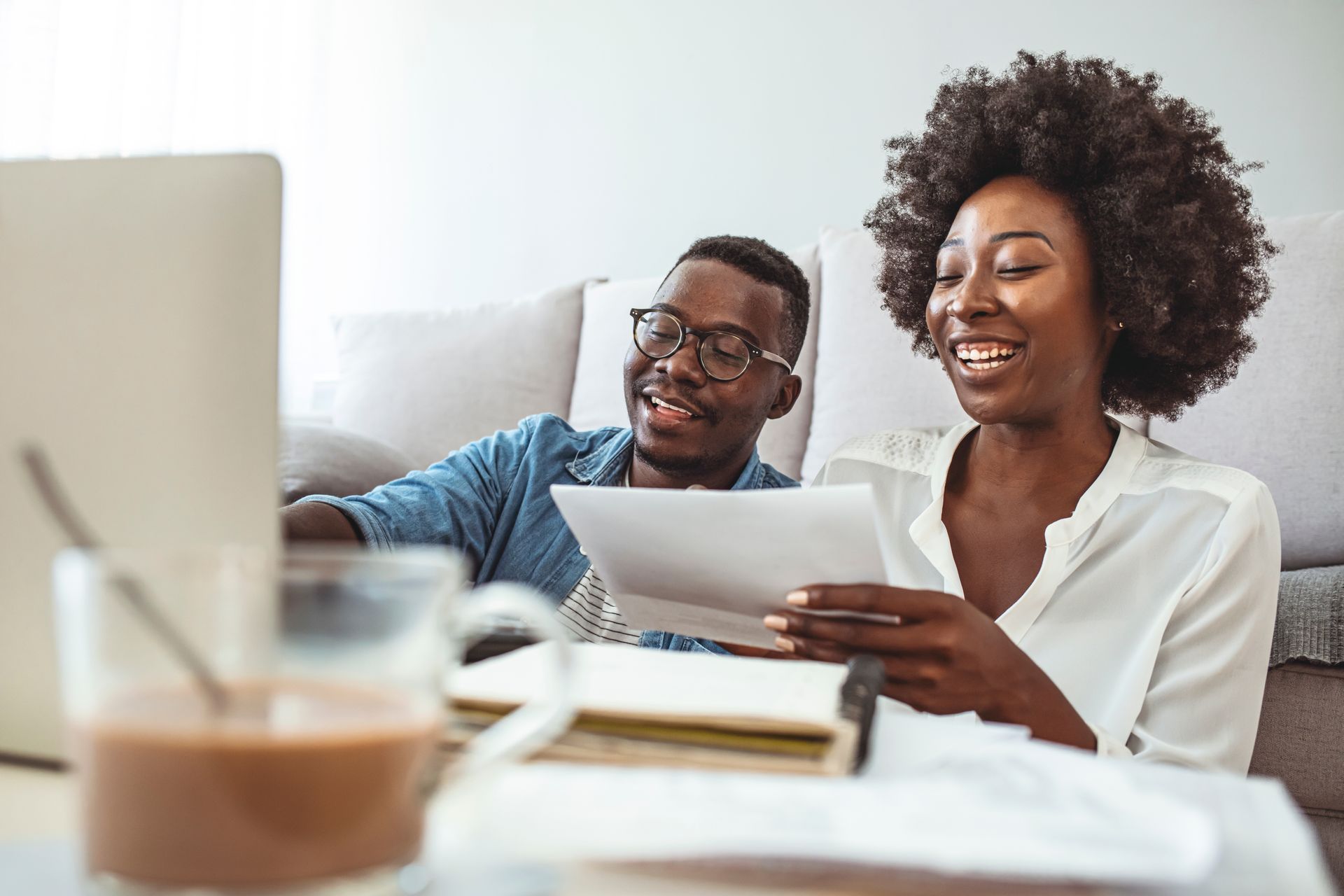 Photograph of a man and woman smiling while reviewing paperwork and working on a laptop.