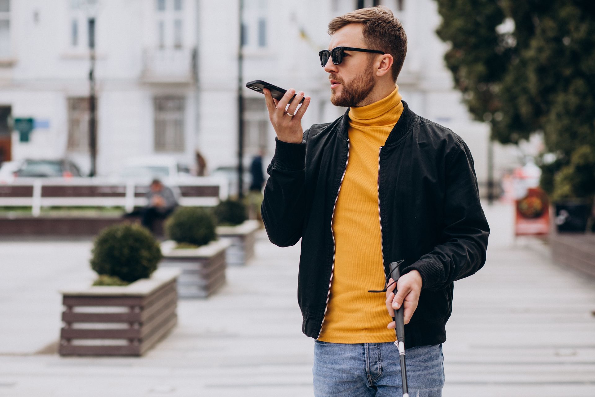 Whilst walking in a park, a man with sight loss uses his mobile phone to record a voice message.