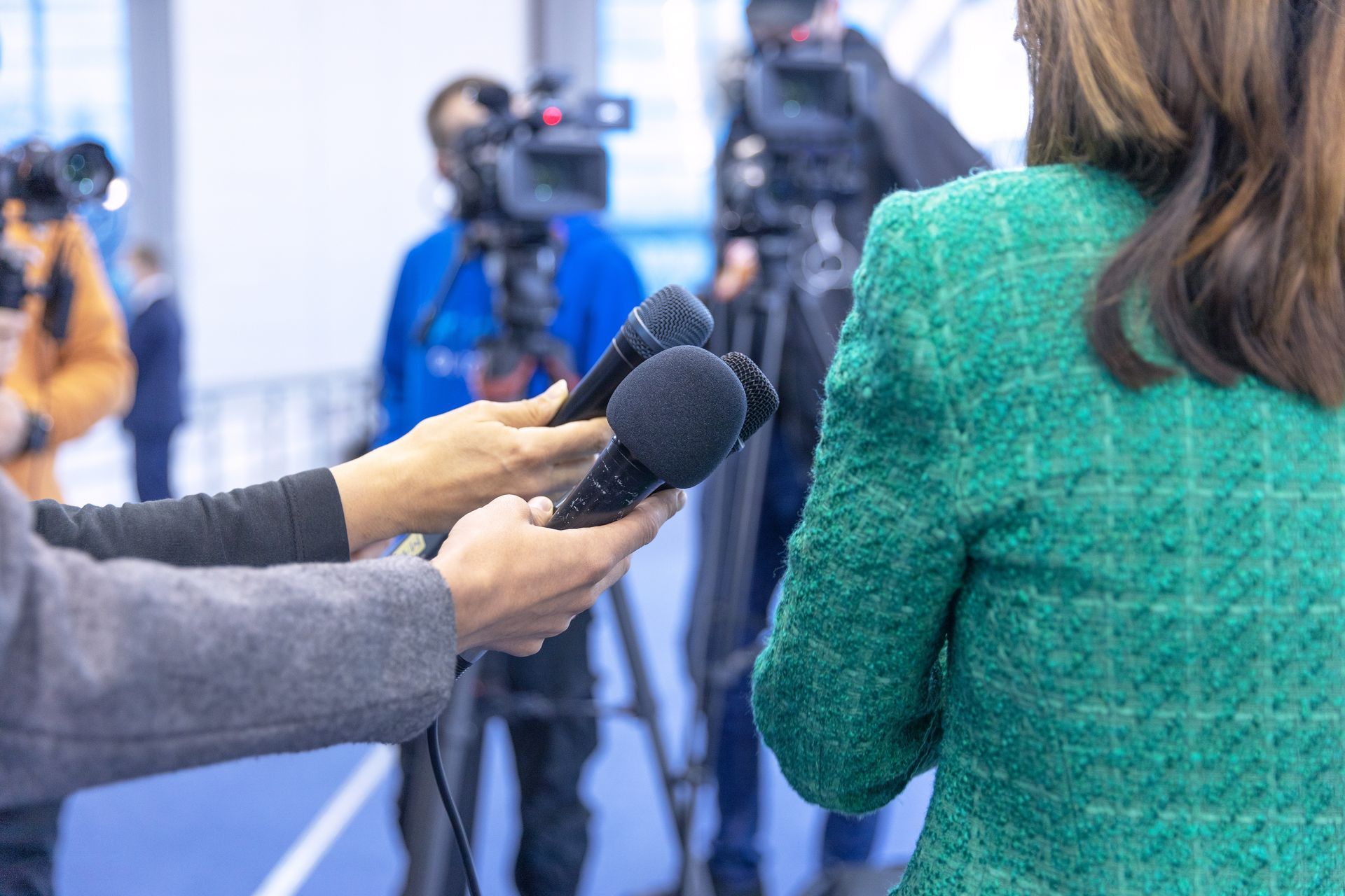 Photograph of reporters interviewing a female politician at a press conference.