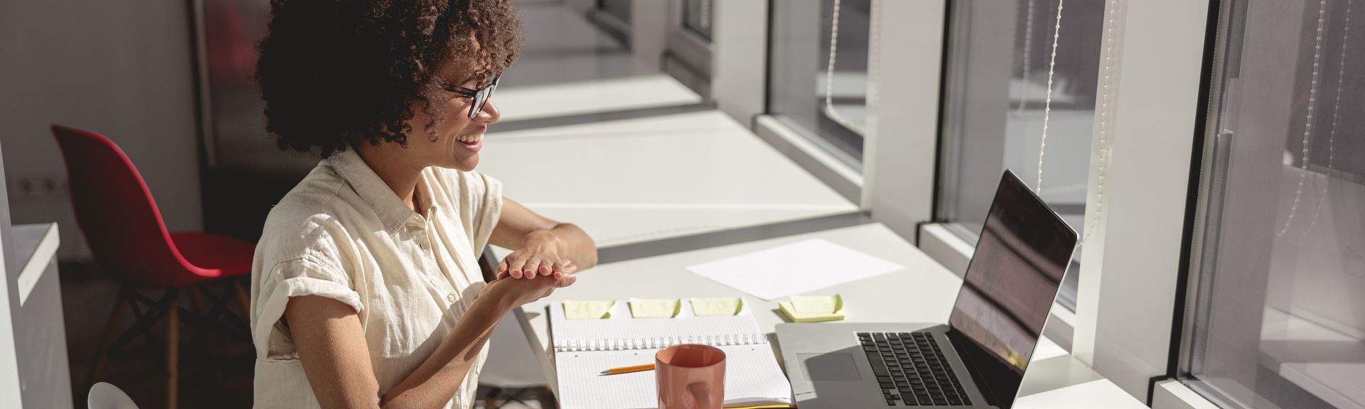 A beaming businesswoman leads a video conference call, communicating using sign language.