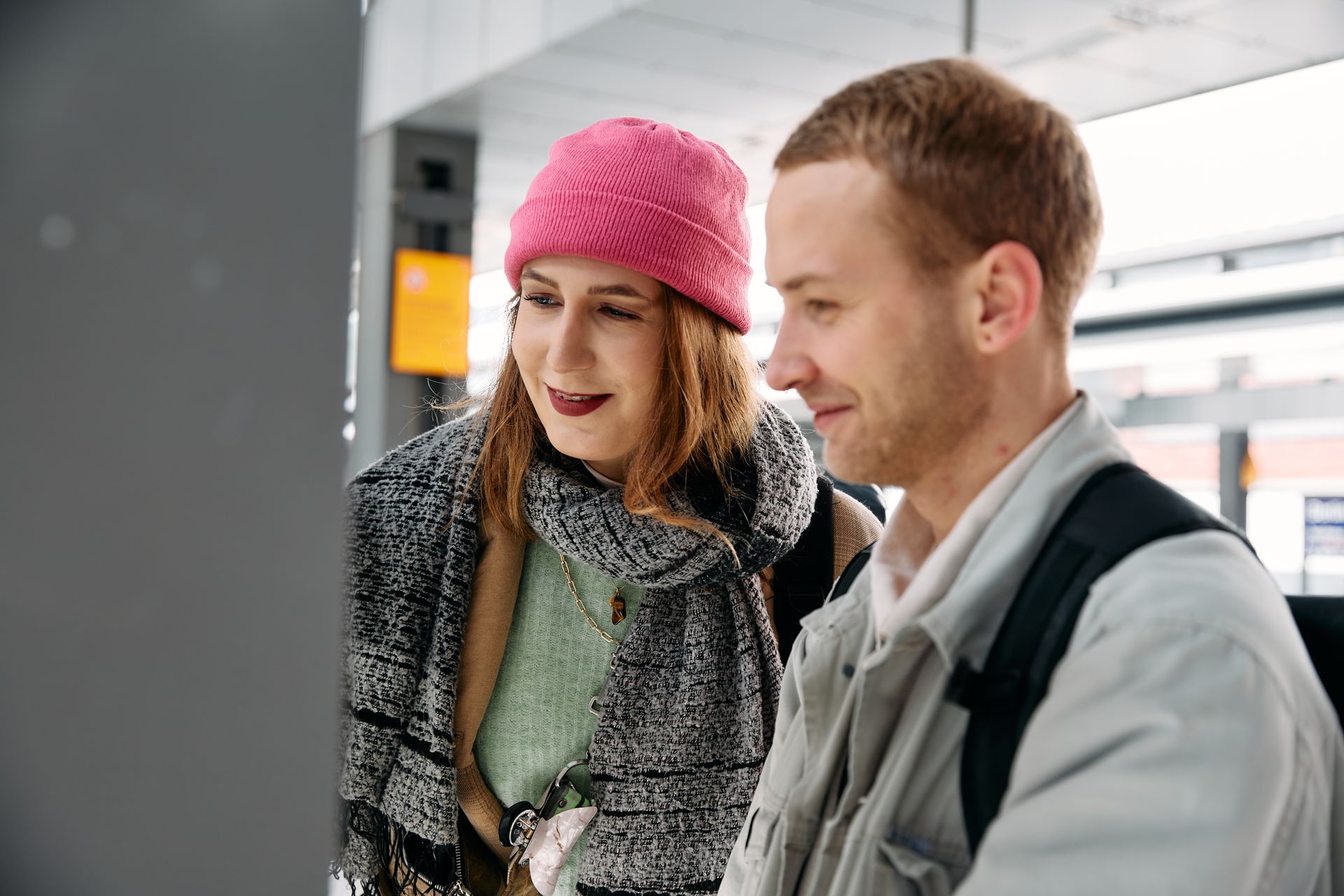 A person passing by stops to help a young man with the digital ticketing booth.