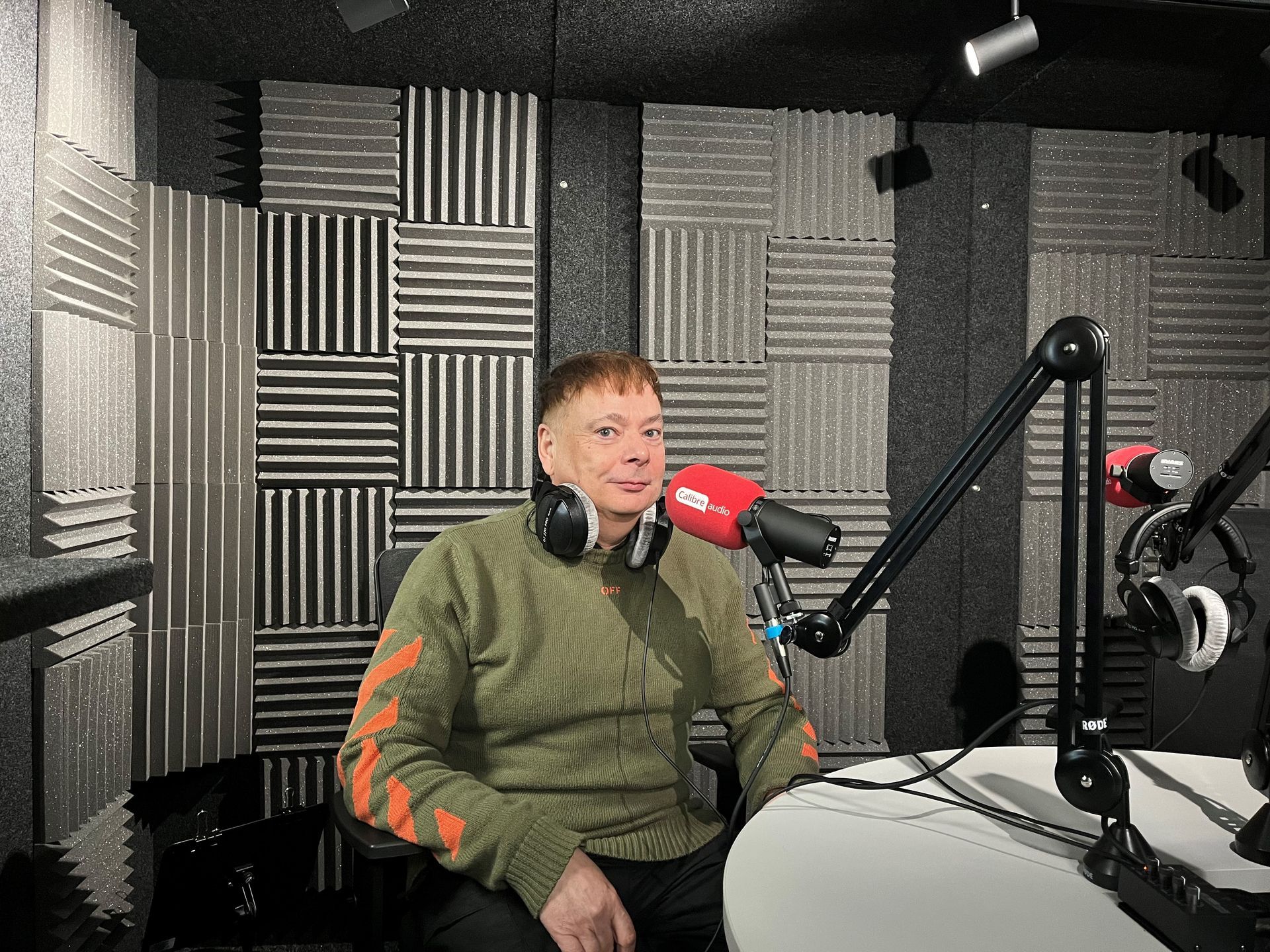 A photo of Calibre's Anthony Kemp sitting in the recording studio with headphones and a microphone.