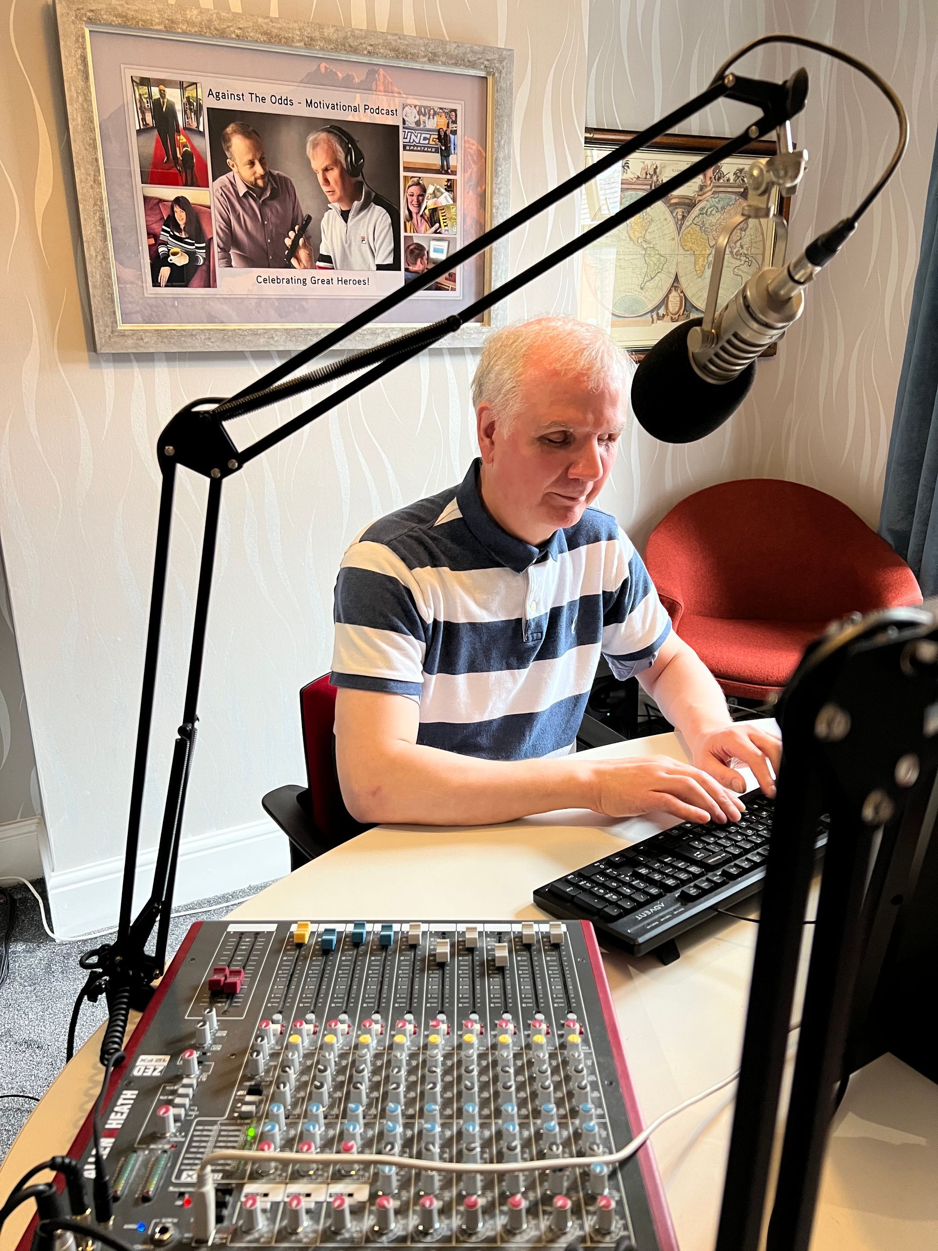 Image: Philip Anderson in recording studio, wearing headphones and speaking into a microphone.