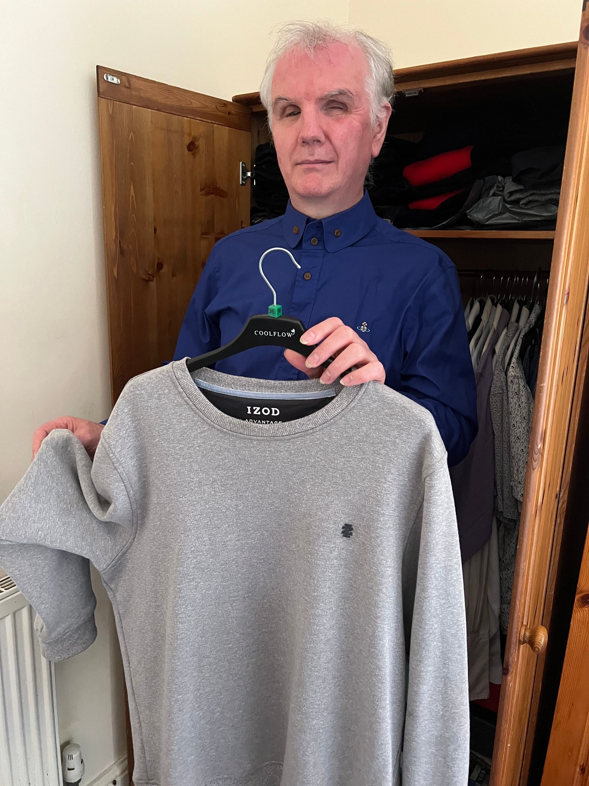Philip Anderson holding up a fleece as he feels the texture of its sleeve.