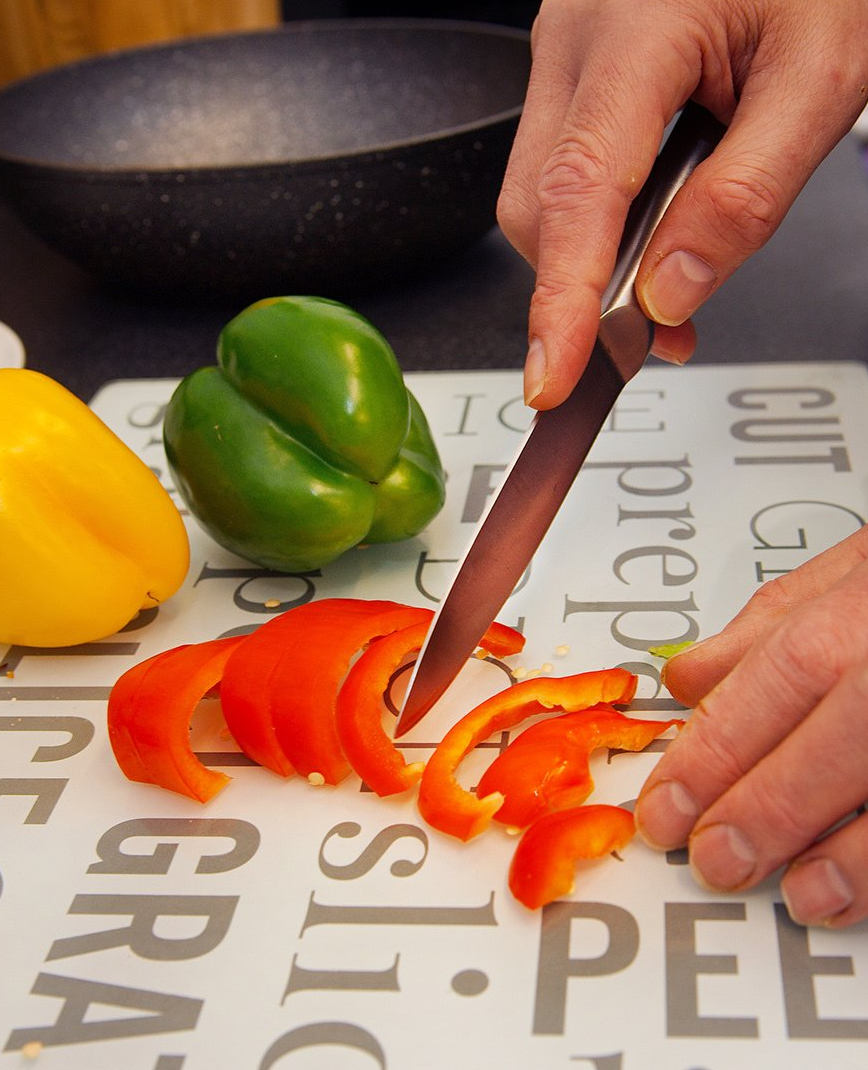 Photograph of Philip Anderson inside a kitchen preparing vegetables independently.