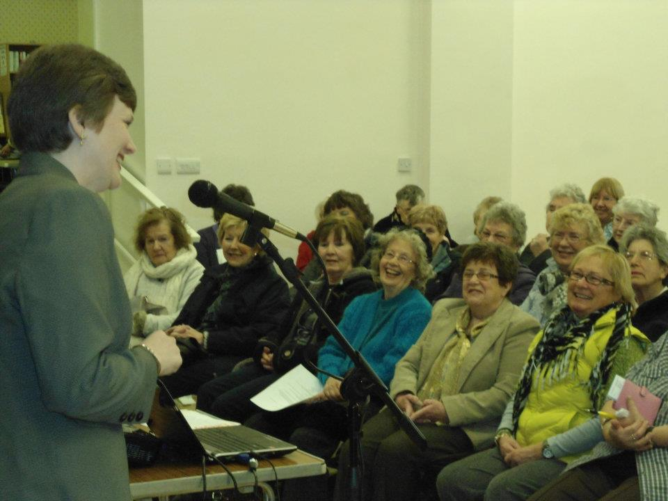 Conference of people smiling and listening to a presenter