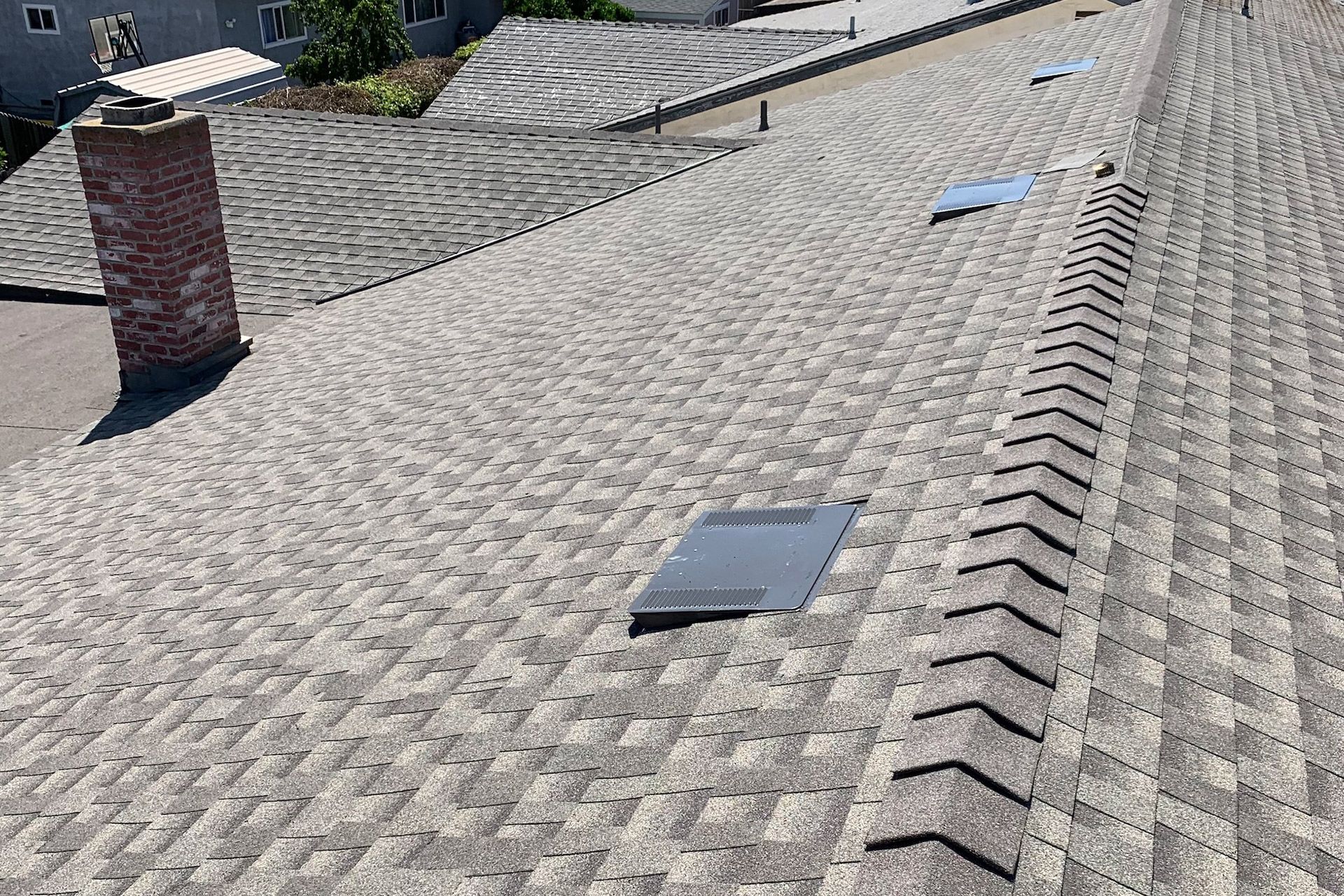 Gray asphalt shingle roof with a brick chimney and three skylights.