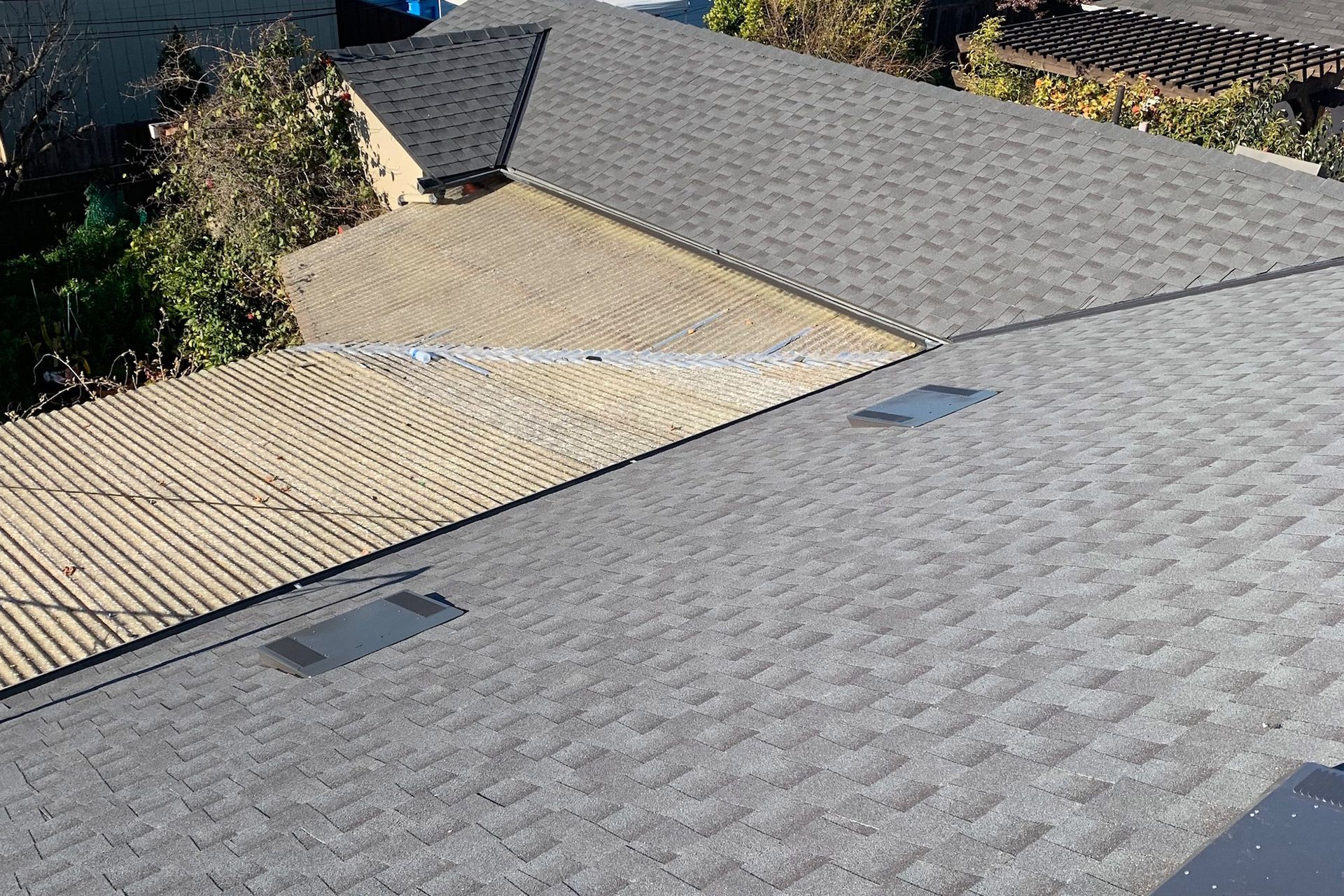 Gray and beige shingled rooftops, with two rectangular vents.