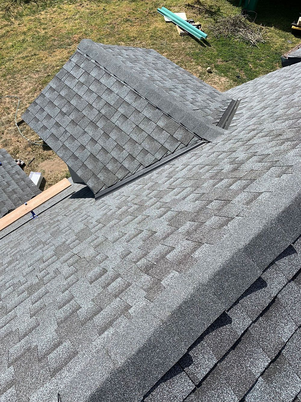 Overhead view of a gray shingle roof with an open section revealing the roof's structure and materials.