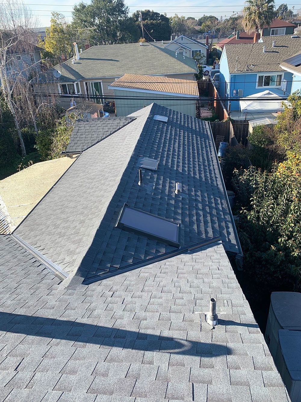 Gray asphalt shingle roofs of houses with varying architectural styles viewed from above.