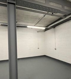 Empty industrial room with white brick walls, gray floor, and exposed ceiling beams