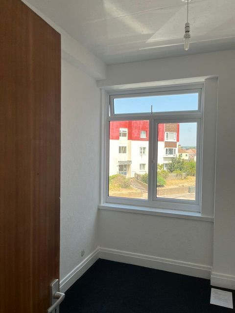 Empty room with three frosted windows, cream walls, and a dark floor.