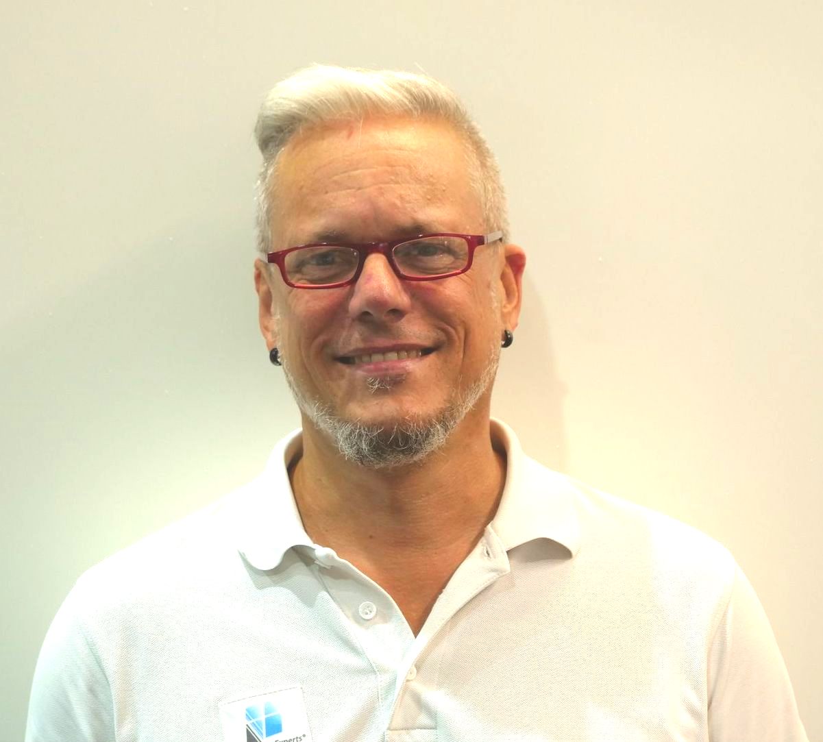 Ein Mann mit Brille und weißem Hemd lächelt in die Kamera.