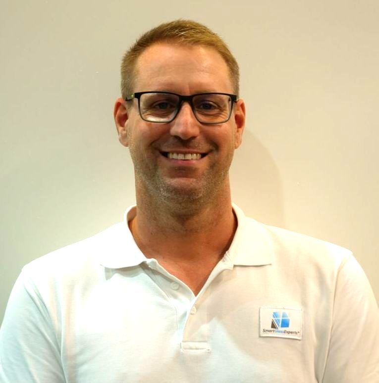Ein lächelnder Mann mit Brille und weißem Hemd