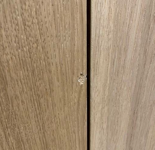 Eine Nahaufnahme einer Holztür mit einem Loch darin.