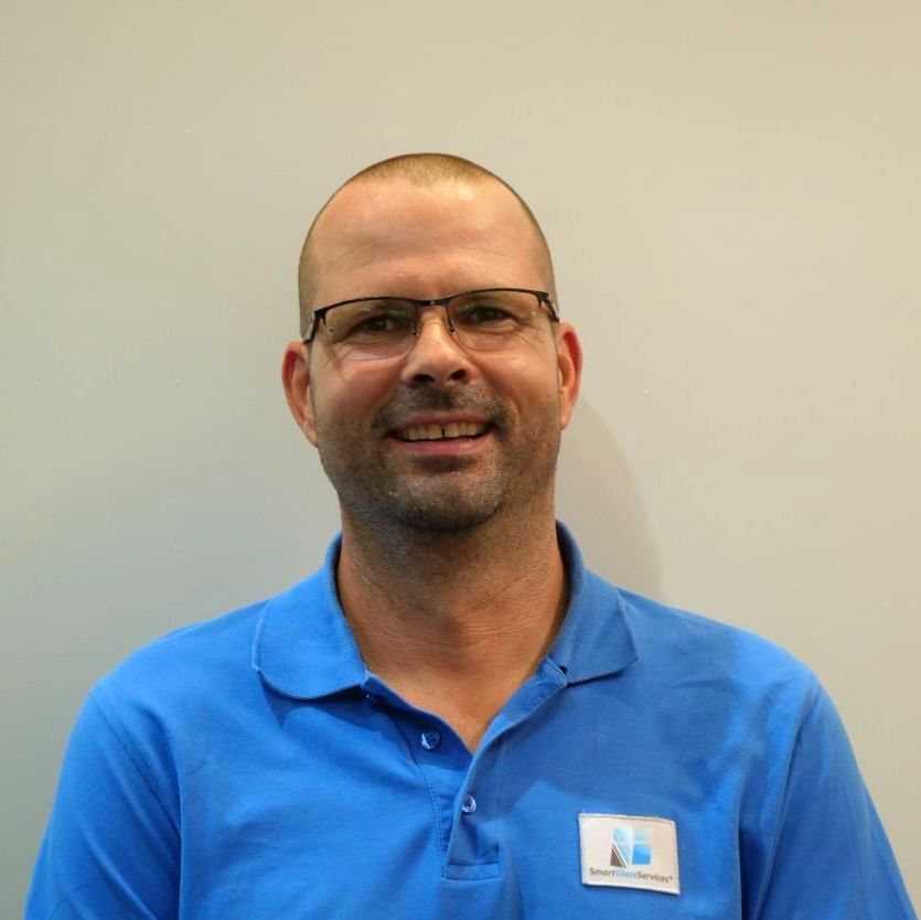 Ein Mann mit Brille und blauem Hemd lächelt in die Kamera