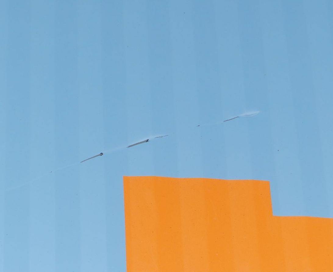 Ein Flugzeug fliegt über einem orangefarbenen Gebäude am Himmel.
