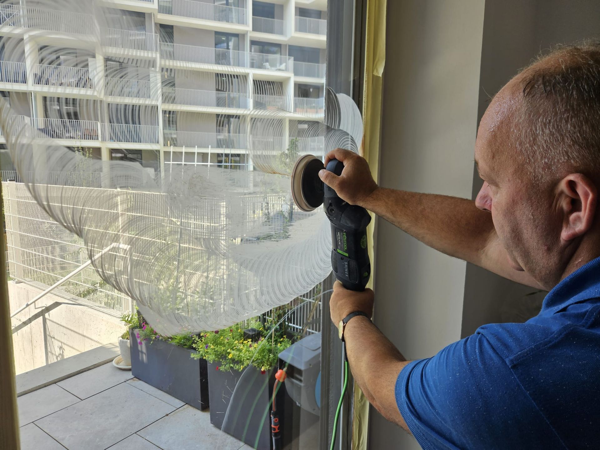 Ein Mann poliert ein Fenster mit einer Maschine.