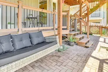 Covered patio with gray sofa, wooden stairs, and brick paver flooring