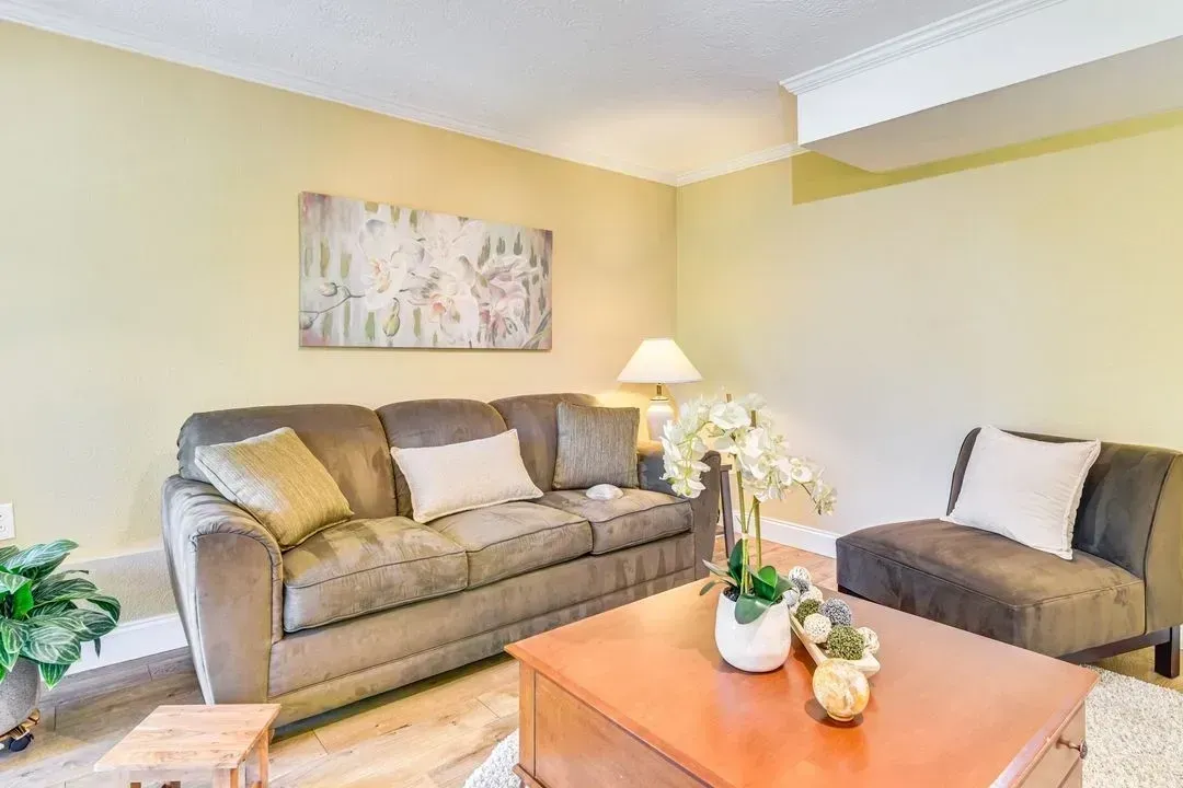 Bright living room with gray sofa, armchair, coffee table, lamp, and light yellow walls
