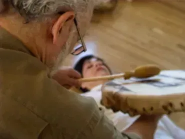 Doctor performing an acupuncture treatment on a patient lying on a table, using a spoon-like tool.