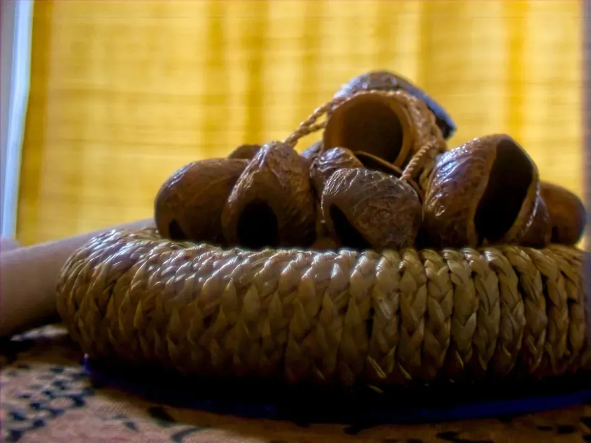 Woven basket holding several brown bread rolls on a table, with a yellow curtain backdrop