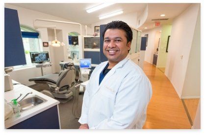 Dentist in white coat smiles in modern dental office.