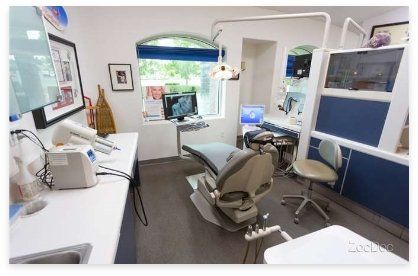 Dental office interior with dental chair, equipment, and window.