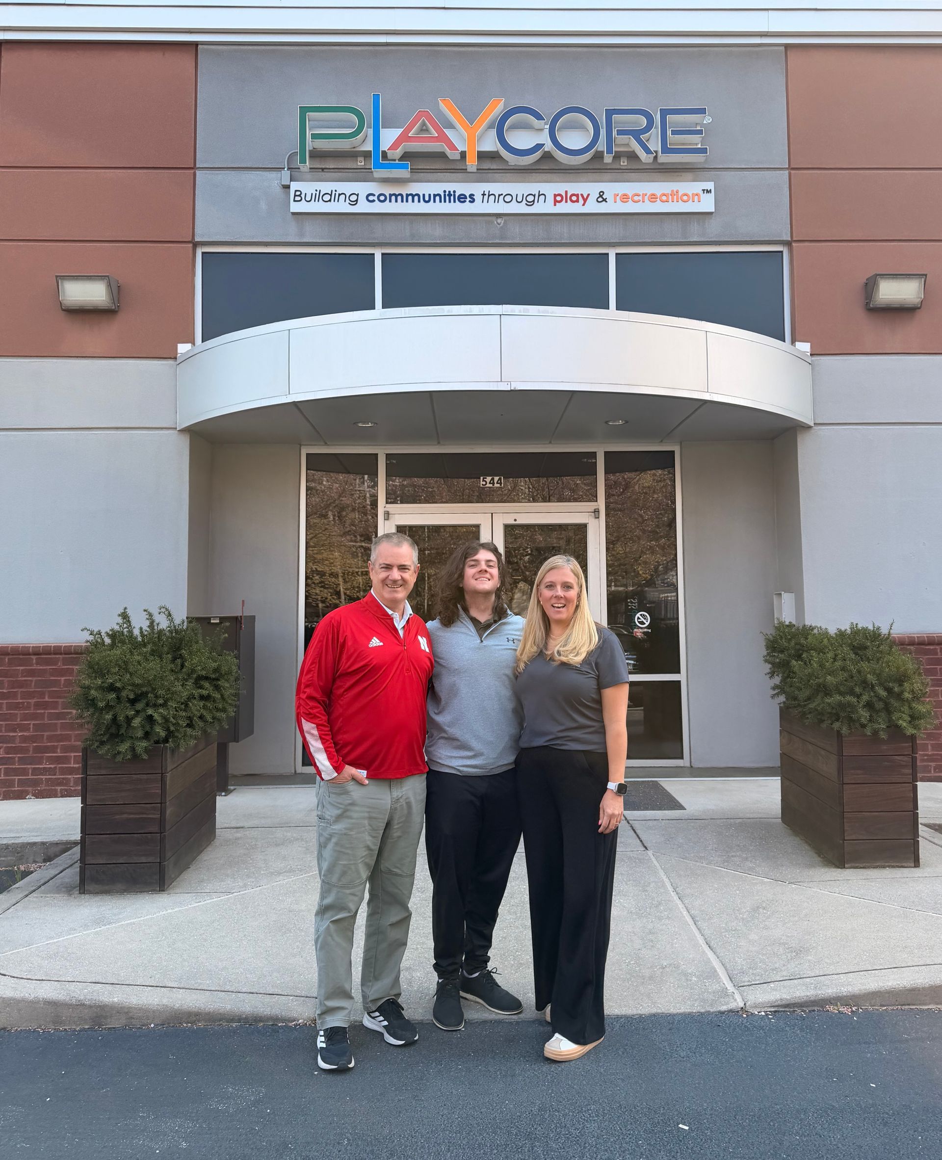 Peak Playscapes team members in business casual attire with green balloon décor