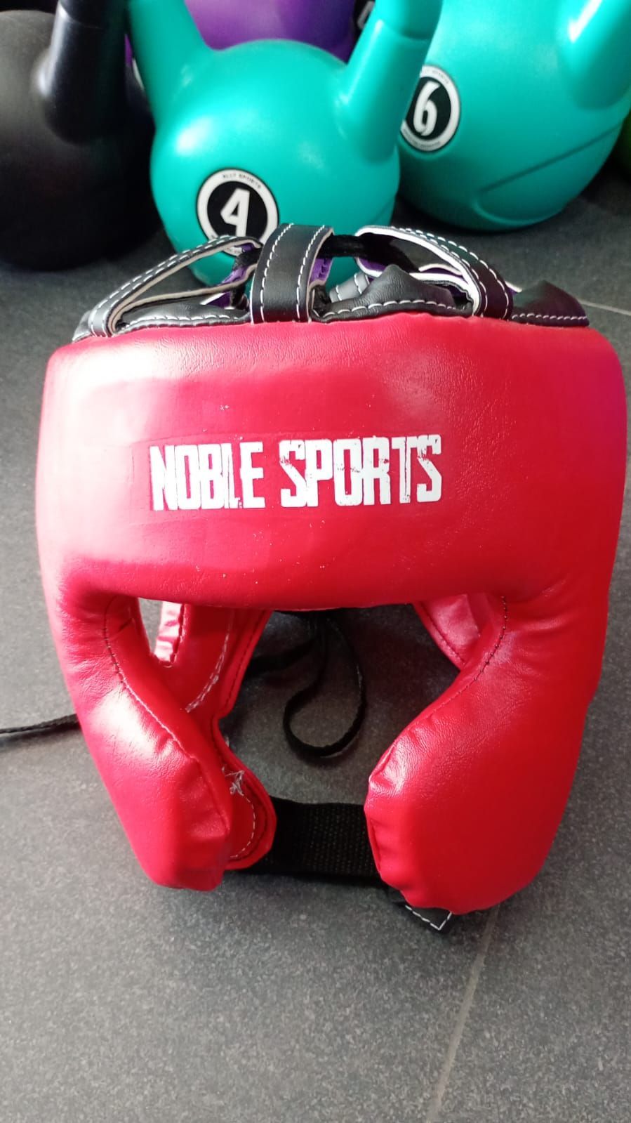 Un casco protector de boxeo rojo con la inscripción 