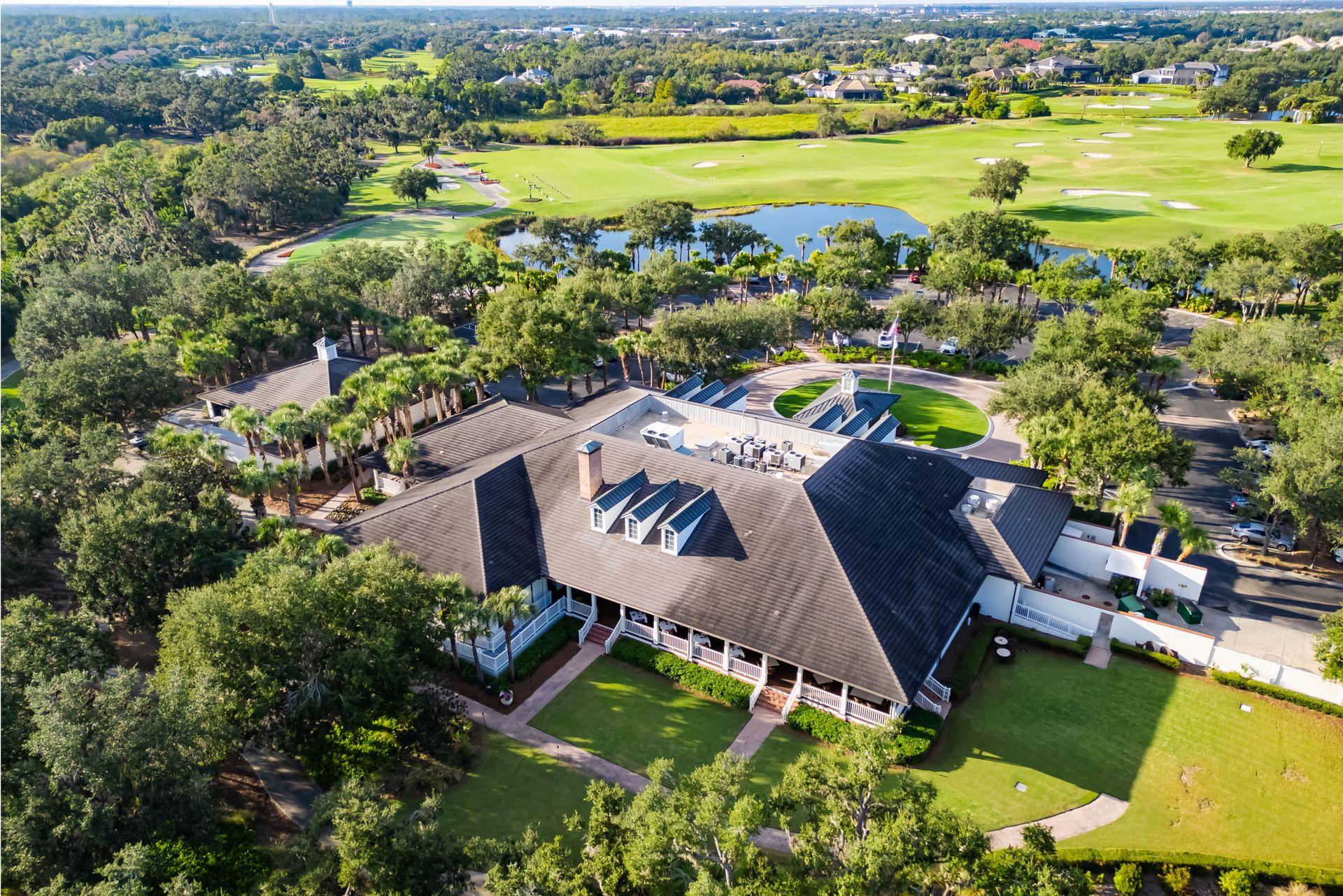 Aerial view of a large thatched-roof building surrounded by trees, lawns, and golf course greens.