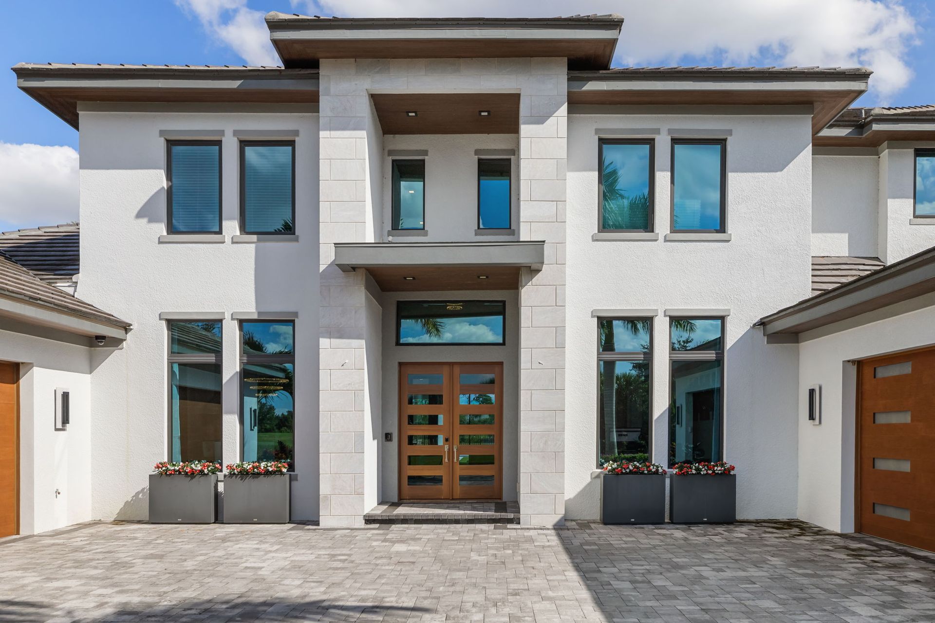 Modern two-story house with white stucco, large windows, and a central wooden front door