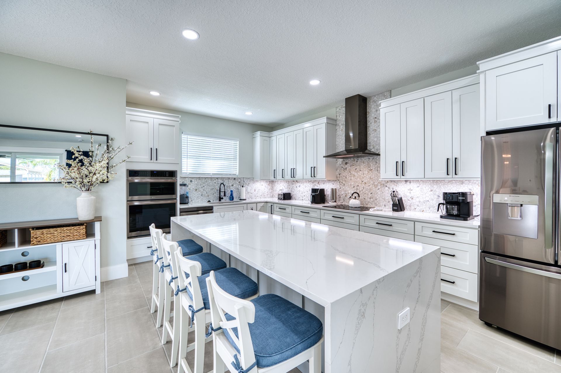 Bright modern kitchen with white cabinets, large island, and stainless steel appliances