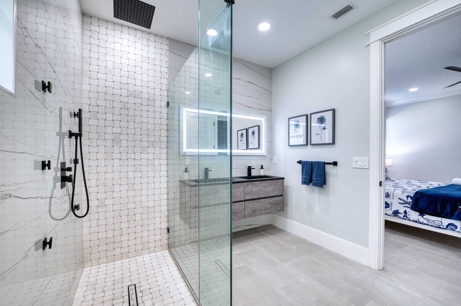 Modern bathroom with glass shower, white tile, floating vanity, and blue towels