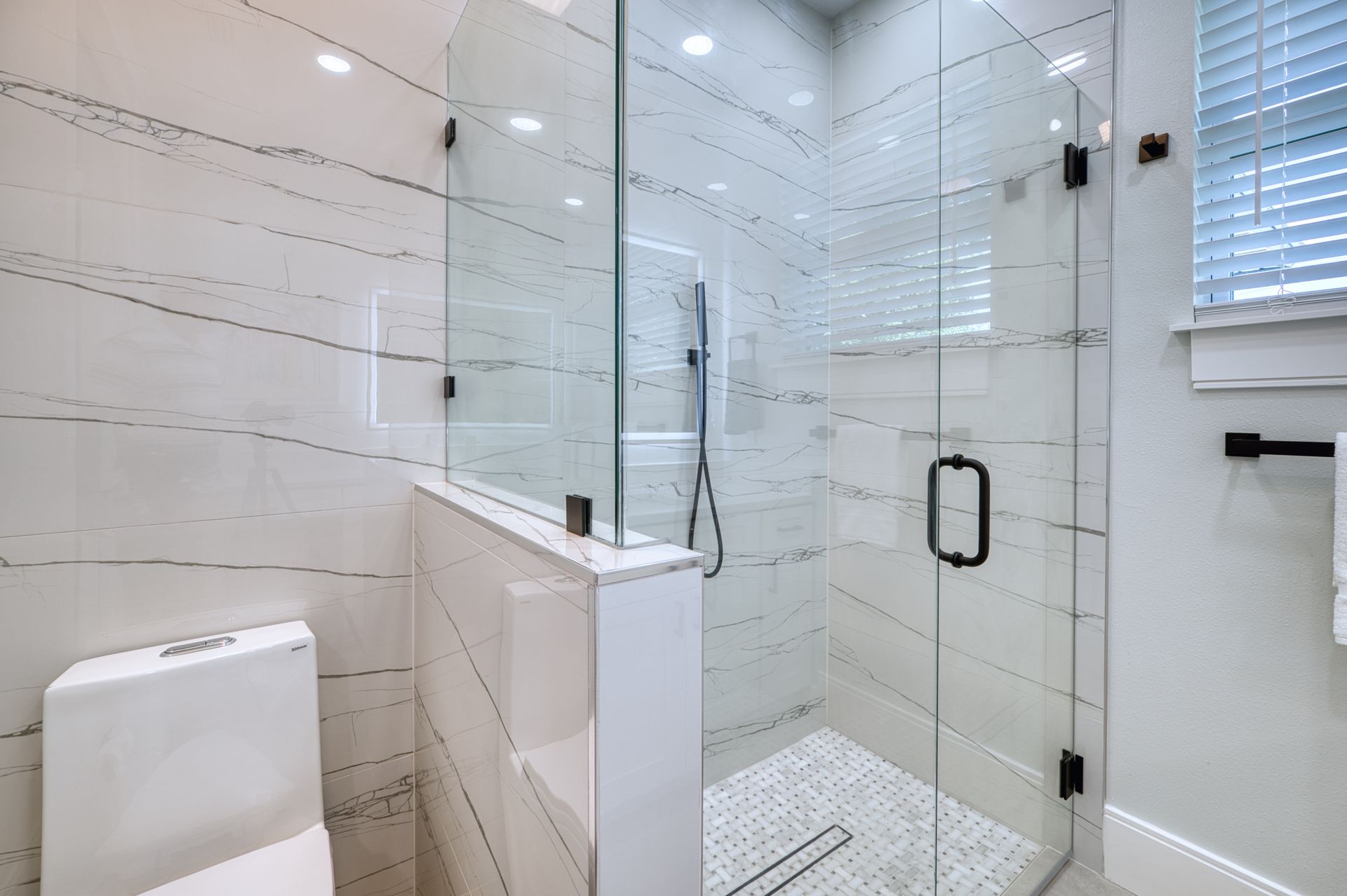 Modern white bathroom with glass-enclosed shower and tiled walls